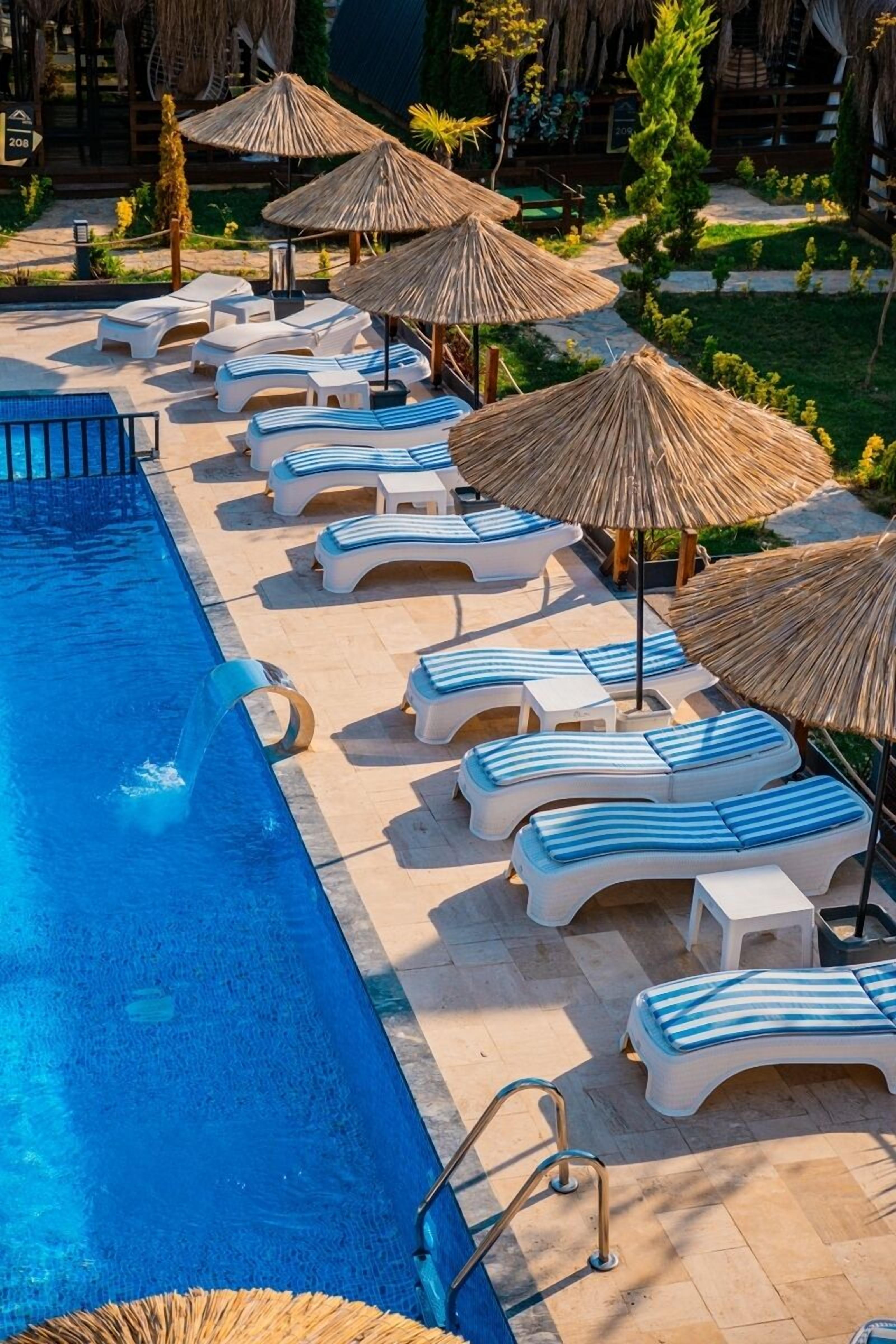 A pool area with lounge chairs and umbrellas.