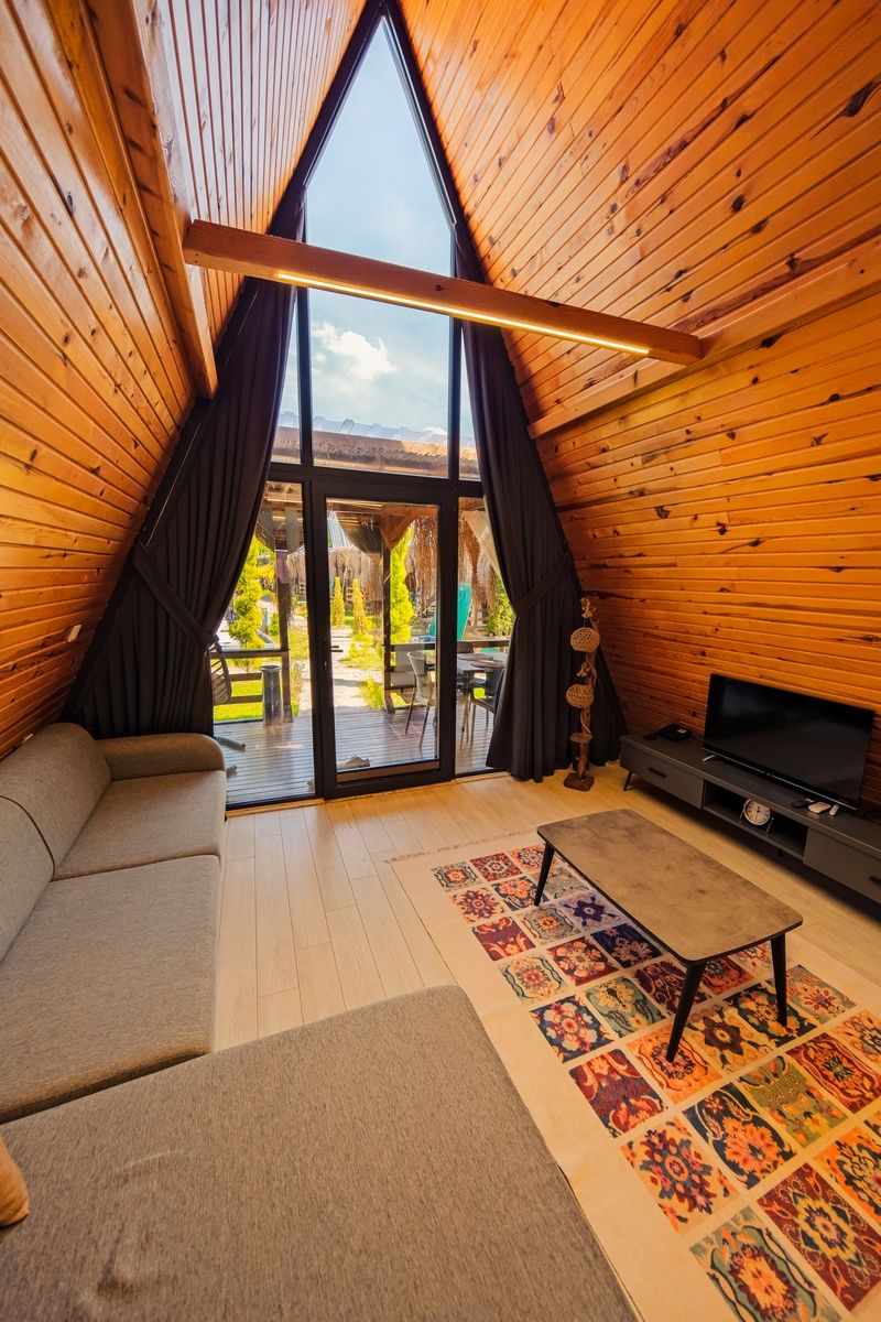 A cozy room with a sloped ceiling, a sofa, a TV, and a patterned rug.