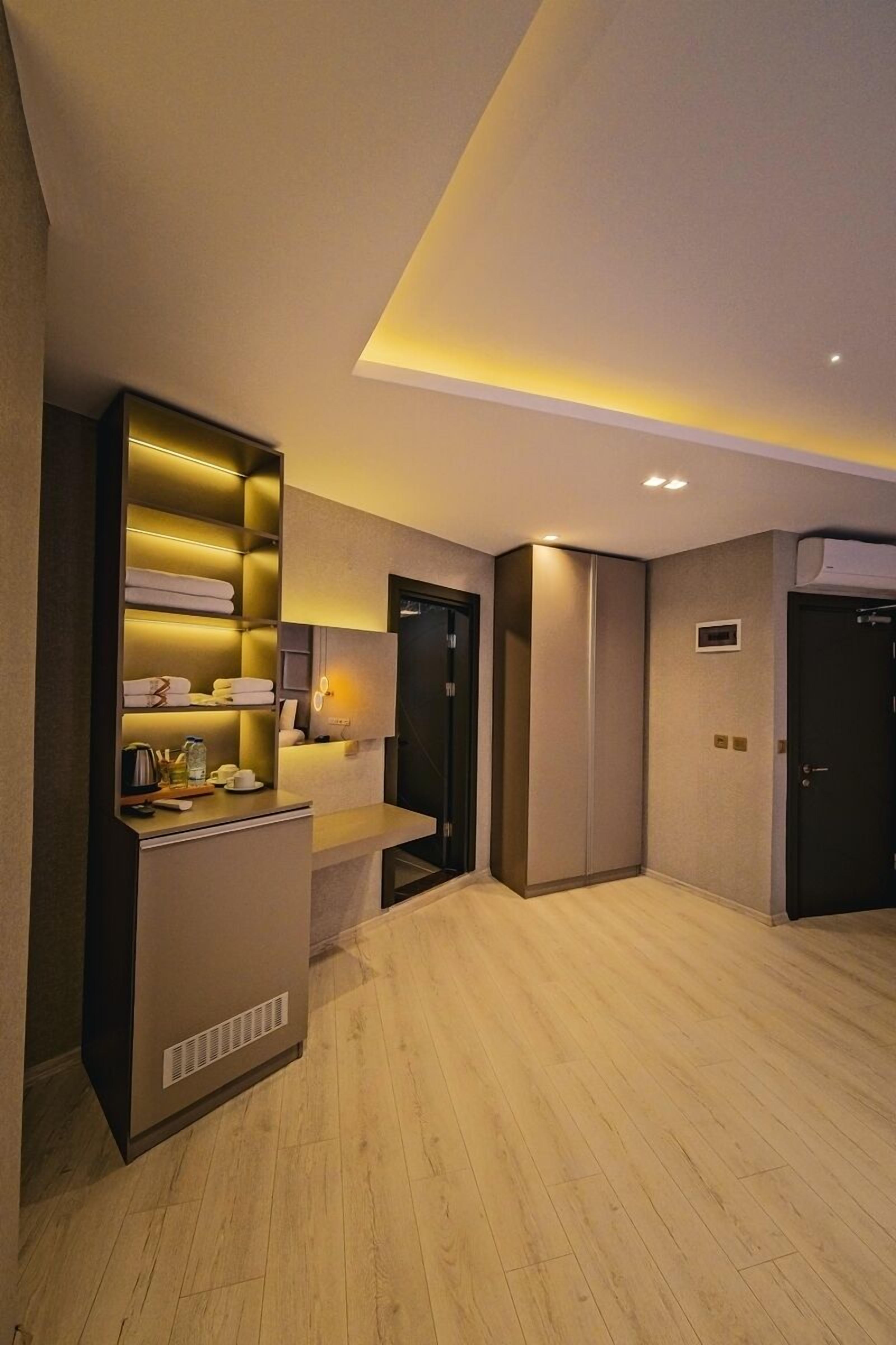 A modern hotel lobby with a reception desk, a built-in shelf with towels, a coat rack, and a door with an air conditioning unit.