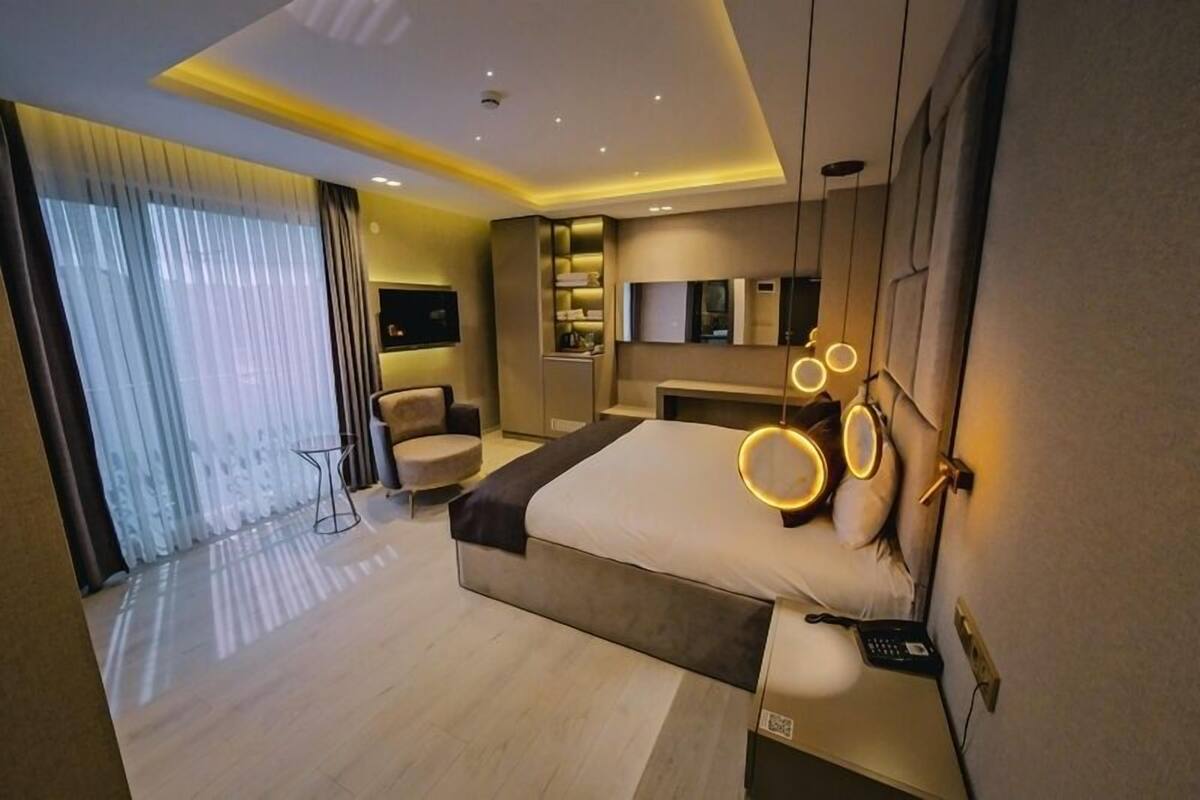 A modern hotel room with a large bed, bedside tables, a desk, and a seating area.