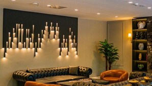 Ein moderner Lounge-Bereich mit einer Sofagarnitur, einem Couchtisch und einer Wand mit vertikalen Leuchten.