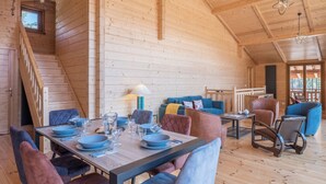 Un interior de madera con una mesa de comedor preparada para cuatro, un sofá y una escalera.
