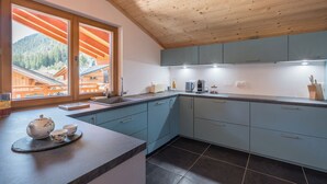 Una cocina moderna con armarios azul claro, encimera oscura y techo de madera.