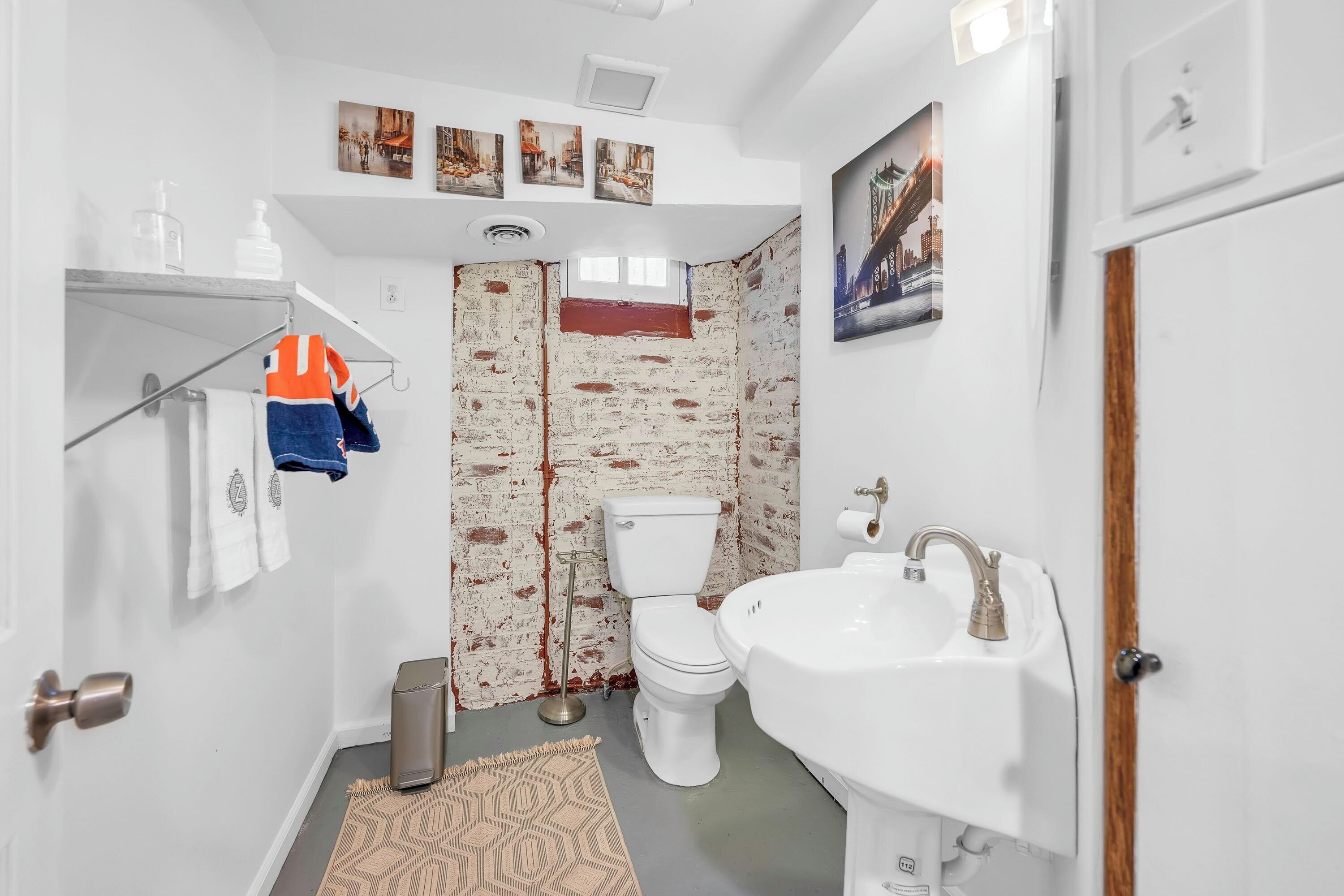 Een badkamer met een wit toilet, een witte wastafel, een douche en een handdoekrek.