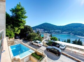 A pool area with a view of a coastal town and mountains. - Villa by the Sea (Dubrovnik)