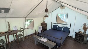 Ein Zeltraum mit einem Bett, einem Tisch, einem Stuhl und einer Bank.