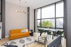 A modern living room with a sofa, dining table, chairs, and a large window with a city view. - Crystal Luxury Apartment  (Porto)