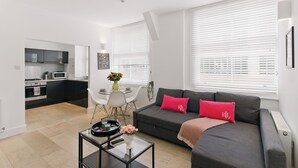 Una sala moderna con un sofá gris, una mesa de centro y un comedor con una mesa y sillas blancas.