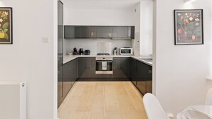 Una cocina moderna con armarios oscuros, un microondas, una estufa y una cafetera.