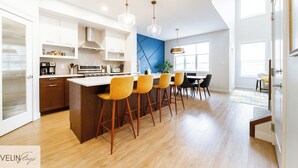 A modern kitchen with a central island, bar stools, and a dining area with a table and chairs.