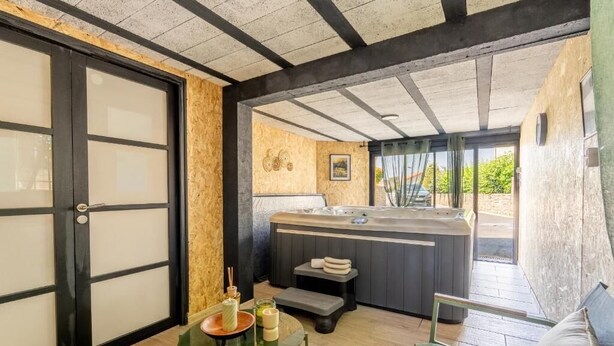 Un área de spa con un jacuzzi, una mesita con velas y un banco.