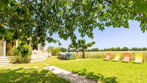 Un jardín cuidado con un patio, mobiliario exterior y vistas al campo.