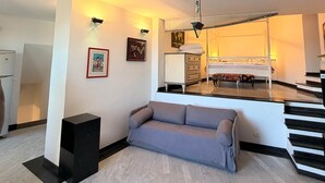 A modern living room with a sofa, a black speaker, and a staircase leading to a bedroom. - Vista Mare Antico [Mura delle Grazie] (Genoa)