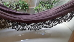 A hammock suspended from a ceiling with a lace-like netting.
