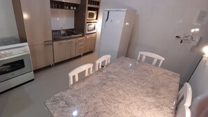 A kitchen with a stove, microwave, refrigerator, and a dining table with chairs.