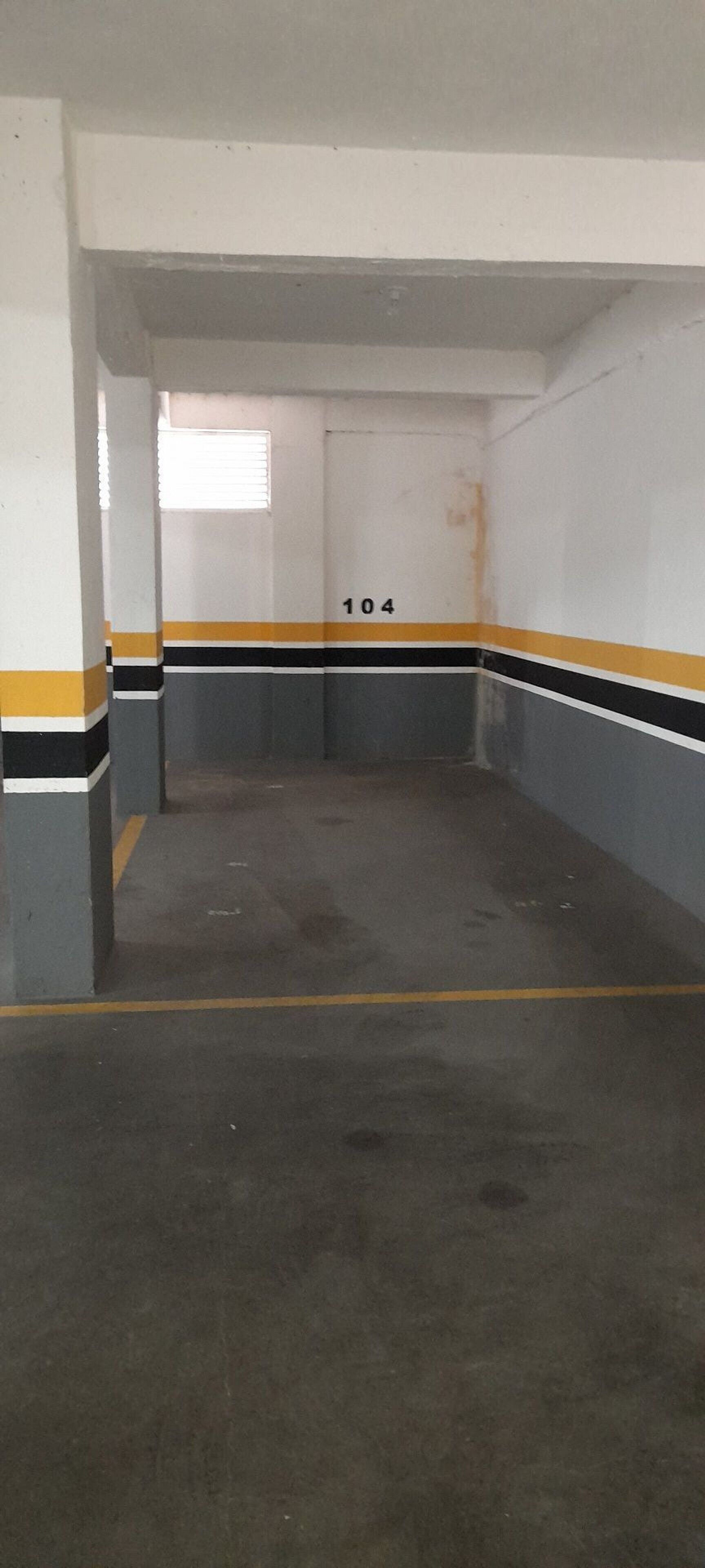 A parking garage with concrete floors, white walls, and yellow and black stripes.