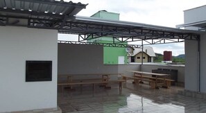 An outdoor patio area with picnic tables and a covered seating area. - Apto 103 Ed Dambros bem localizado (Piratuba)