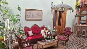 Un salon traditionnel avec un canapé rouge, des chaises en bois, une table basse et un sol à motifs.