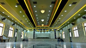 A spacious hall with a polished marble floor, a central chandelier, and a symmetrical ceiling design with recessed lighting. - Jothi Mahal (Tiruvannamalai)