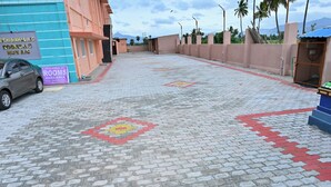 A paved walkway with patterned tiles, a parked car, and signs advertising available rooms. - Jothi Mahal (Tiruvannamalai)