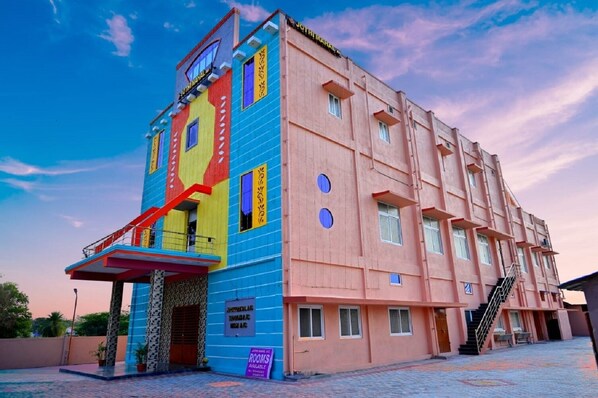 Un immeuble à plusieurs étages, doté d’une façade colorée, d’un escalier et d’une enseigne indiquant les chambres disponibles.
