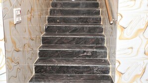A staircase with black marble steps and a handrail, leading to a room with marble walls. - Jothi Mahal (Tiruvannamalai)