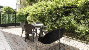 An outdoor seating area with a table and chairs, a black chair, and a metal frame structure.