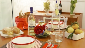 A dining table set with plates, glasses, a bottle of wine, and a bowl of lemons.