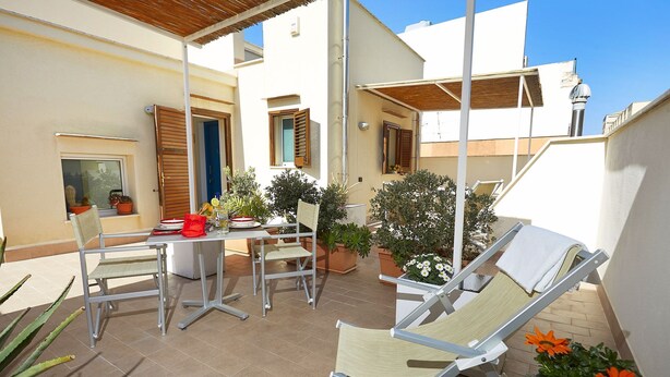 A patio area with a table, chairs, and potted plants.