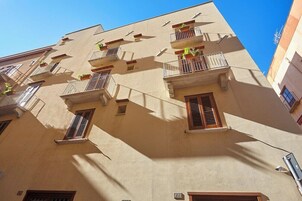 Un edificio de varios pisos con balcones, ventanas y un cielo despejado.