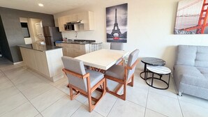 A modern kitchen with a central island, dining area with a table and chairs, and a sofa. - Torre Revolución Sutaj Centro (Guadalajara)