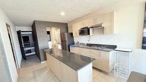 A modern kitchen with a central island, stainless steel appliances, and light wood cabinetry. - Torre Revolución Sutaj Centro (Guadalajara)