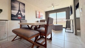 A dining area with a table and chairs, a ceiling fan, and artwork of the Eiffel Tower and Golden Gate Bridge. - Torre Revolución Sutaj Centro (Guadalajara)
