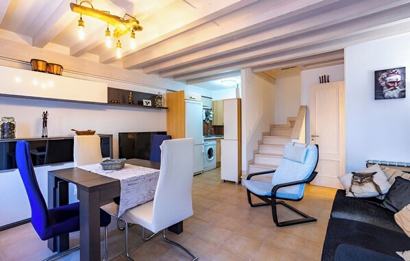 Een moderne woonkamer met een eethoek, een trap en een keuken op de achtergrond.