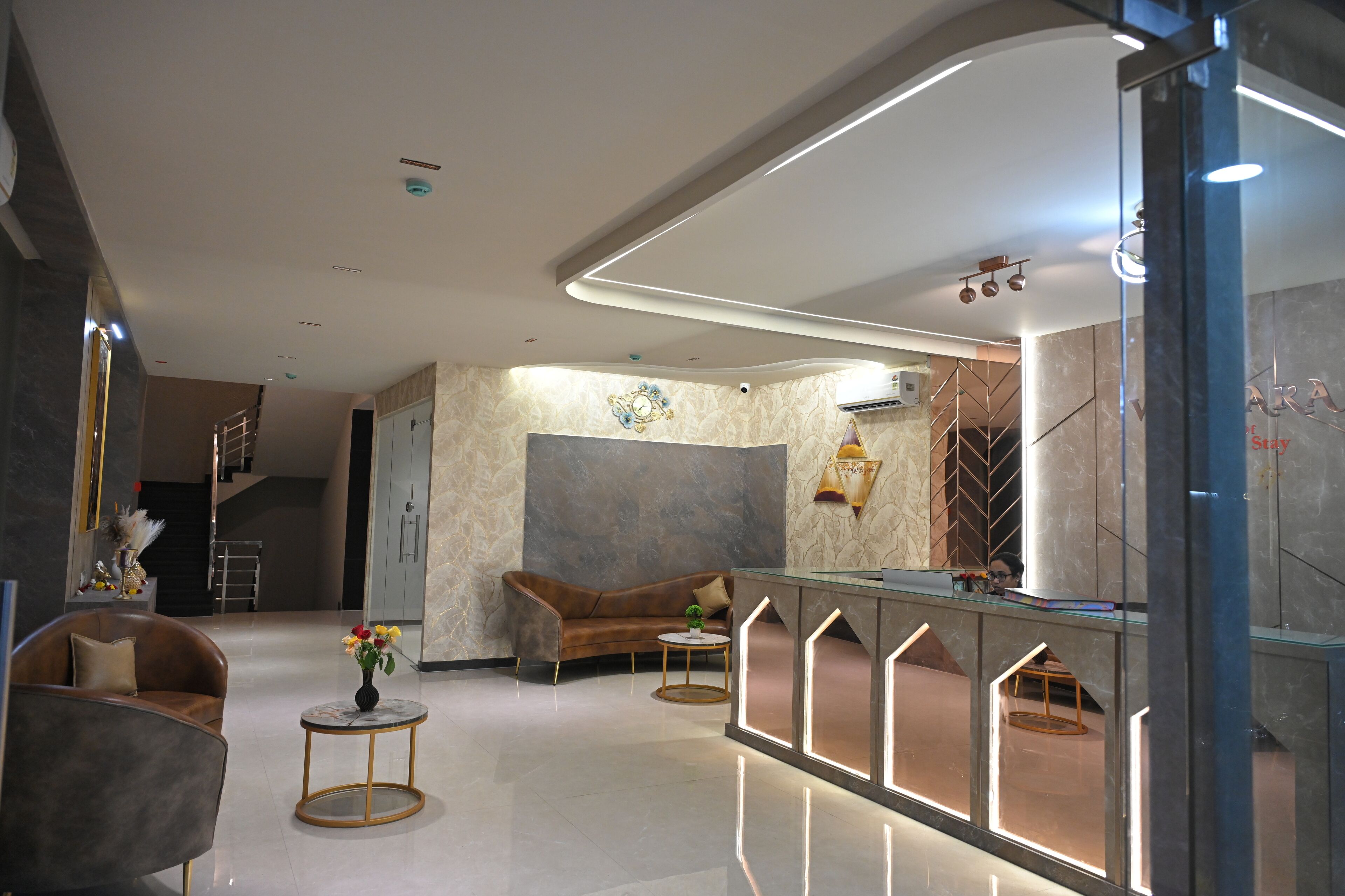 A modern hotel lobby with a curved reception desk, a sofa, and a coffee table.