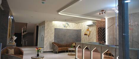 A modern hotel lobby with a curved reception desk, a sofa, and a coffee table.