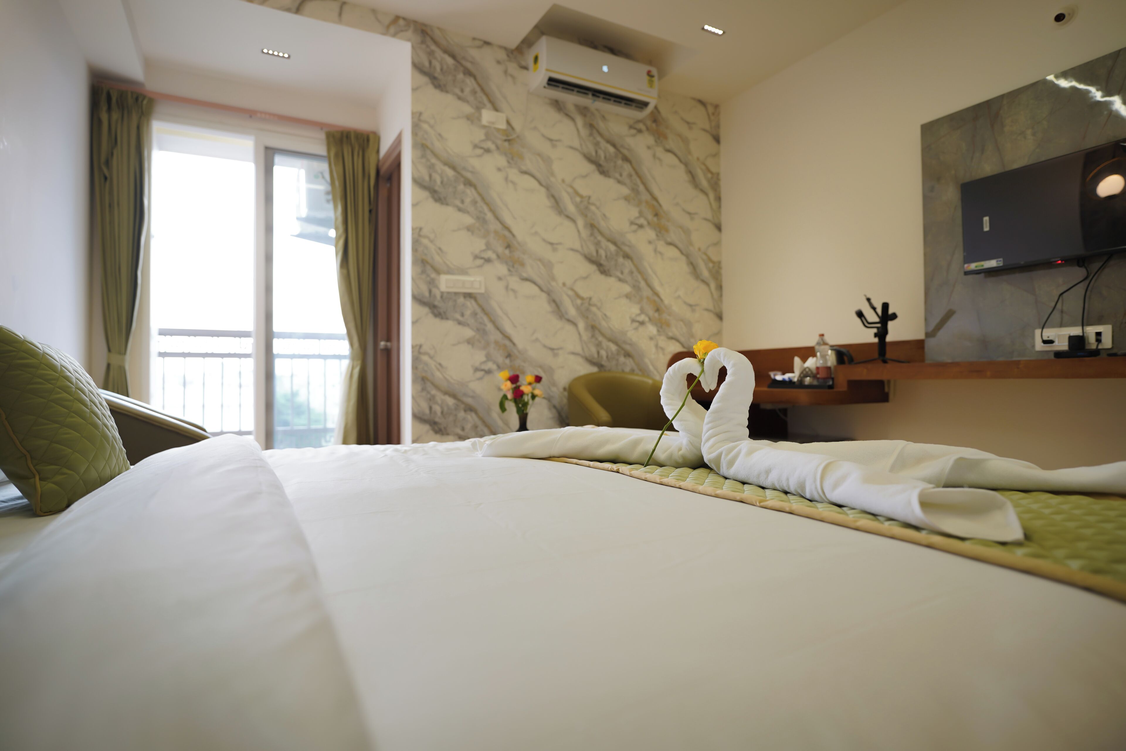 Une chambre d’hôtel avec un lit soigneusement fait, un téléviseur à écran plat fixé au mur et une fenêtre avec des rideaux.