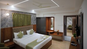 A modern hotel room with a large bed, a ceiling fan, a TV, and a small desk area. - VISTHARA a unit of Suraksha Stay (Bangalore)
