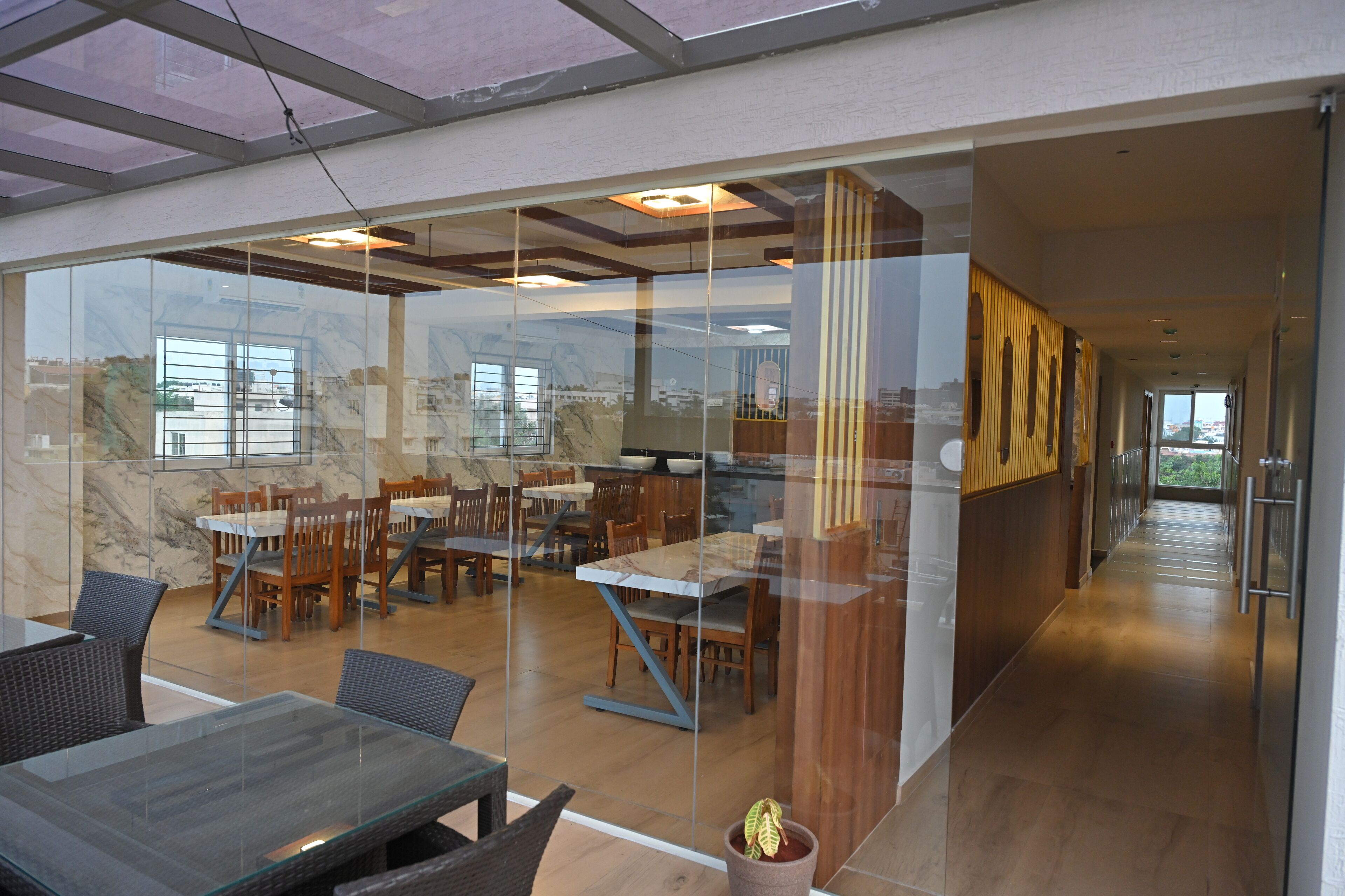 Un comedor moderno con divisiones de vidrio, muebles de madera y vistas a la ciudad.