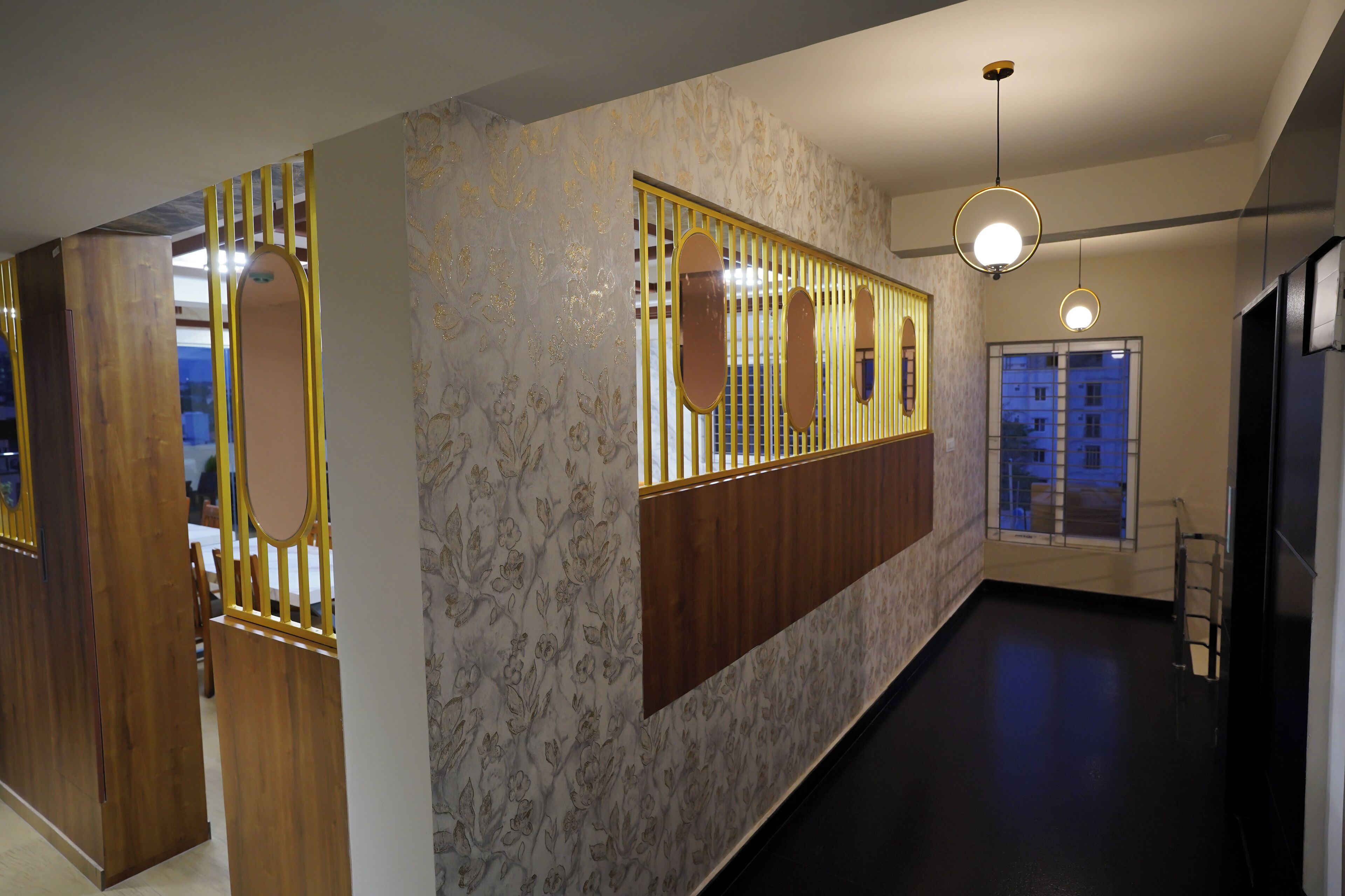 A hallway with a decorative wooden partition, patterned wallpaper, and pendant lighting.
