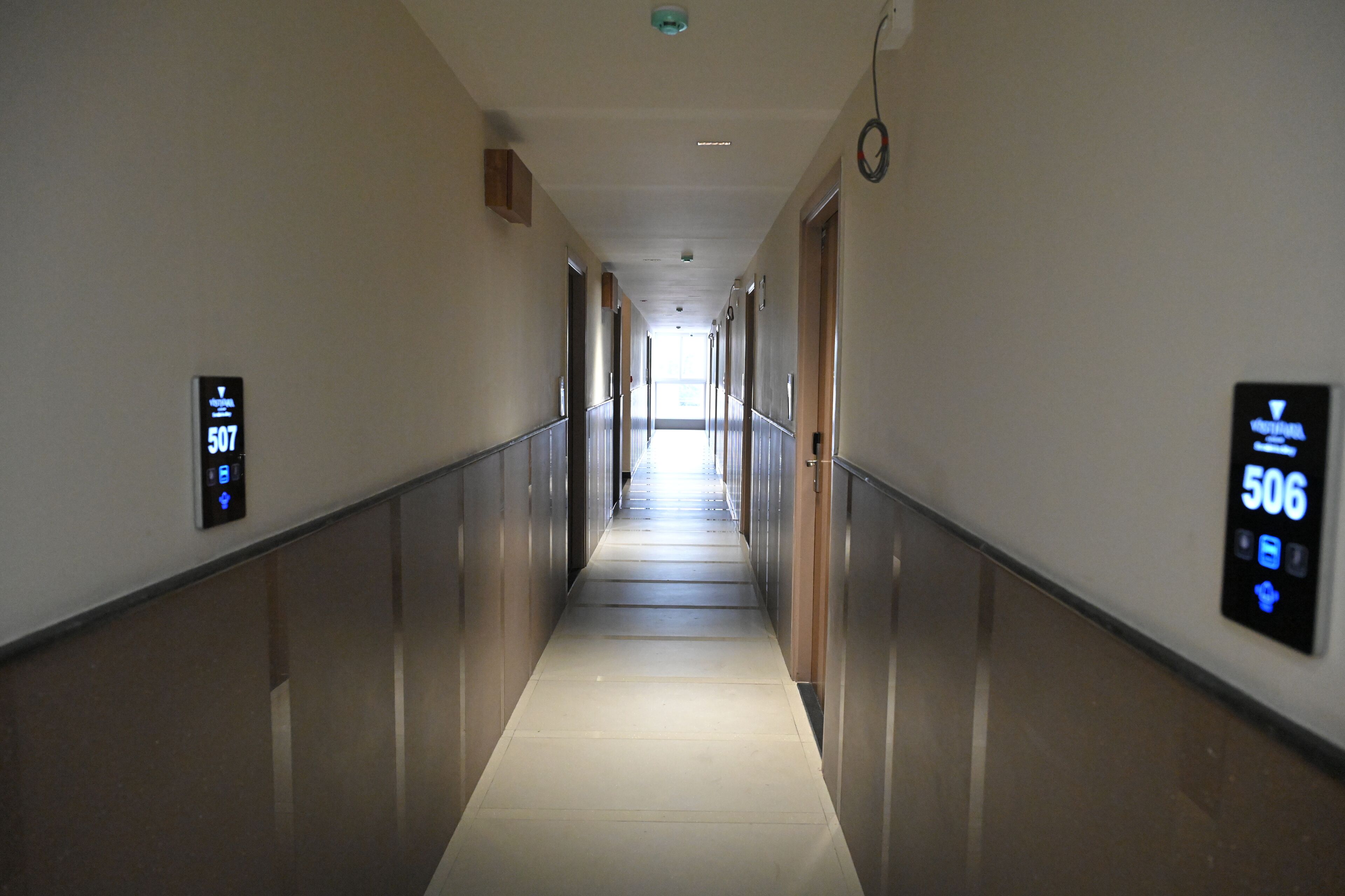 A long, narrow hallway with a reflective floor and walls, flanked by doors on either side.