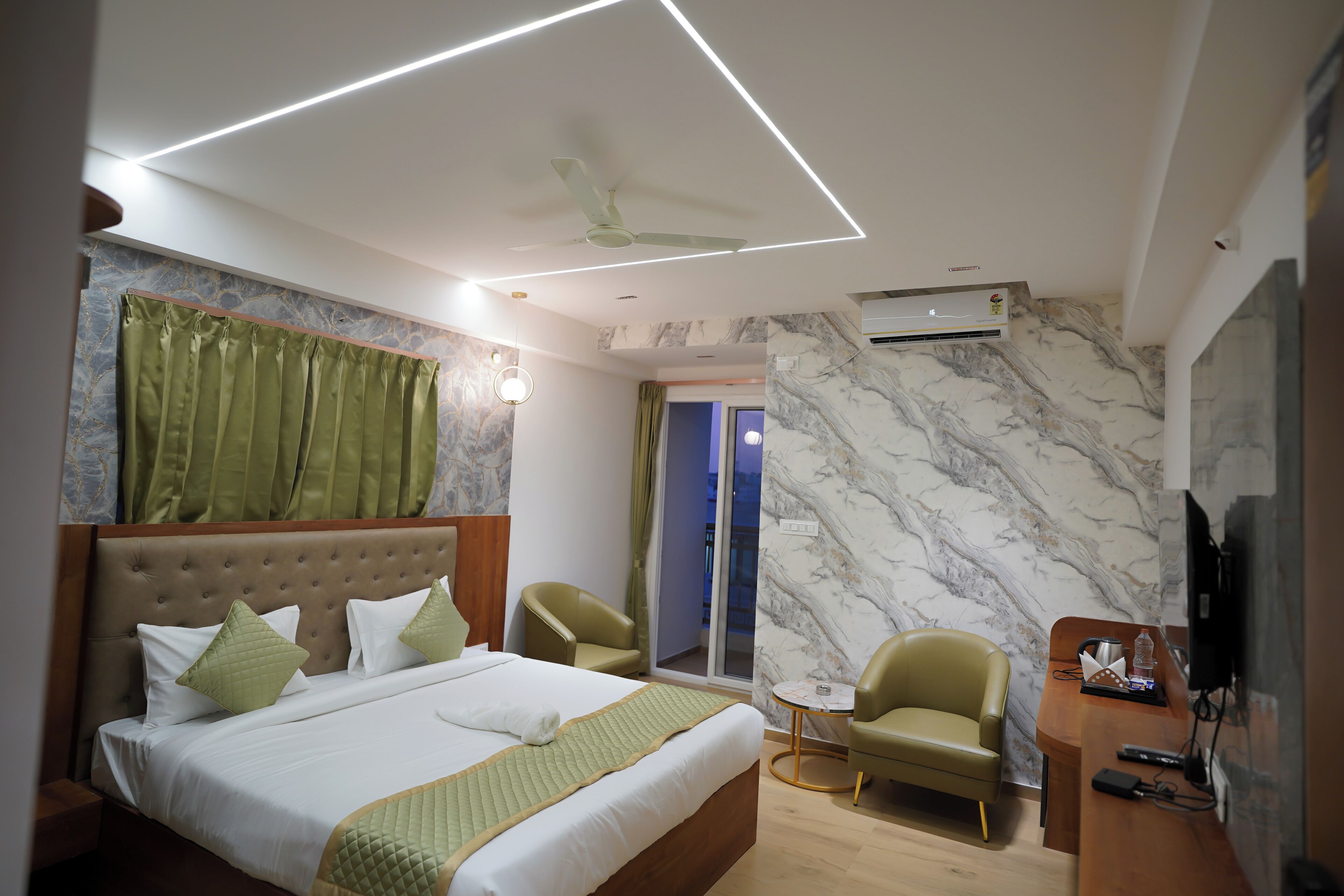 A modern hotel room with a large bed, a desk, a chair, and a television.