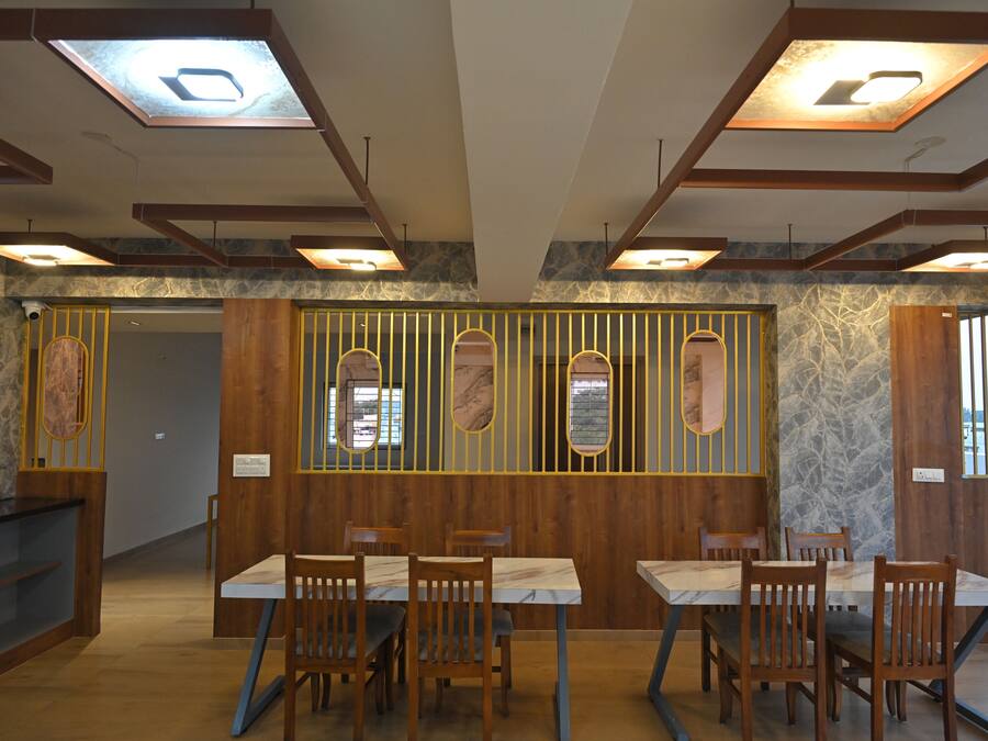 Ein Restaurant mit Holzwandverkleidung, Marmortischen und einer Steinwand.