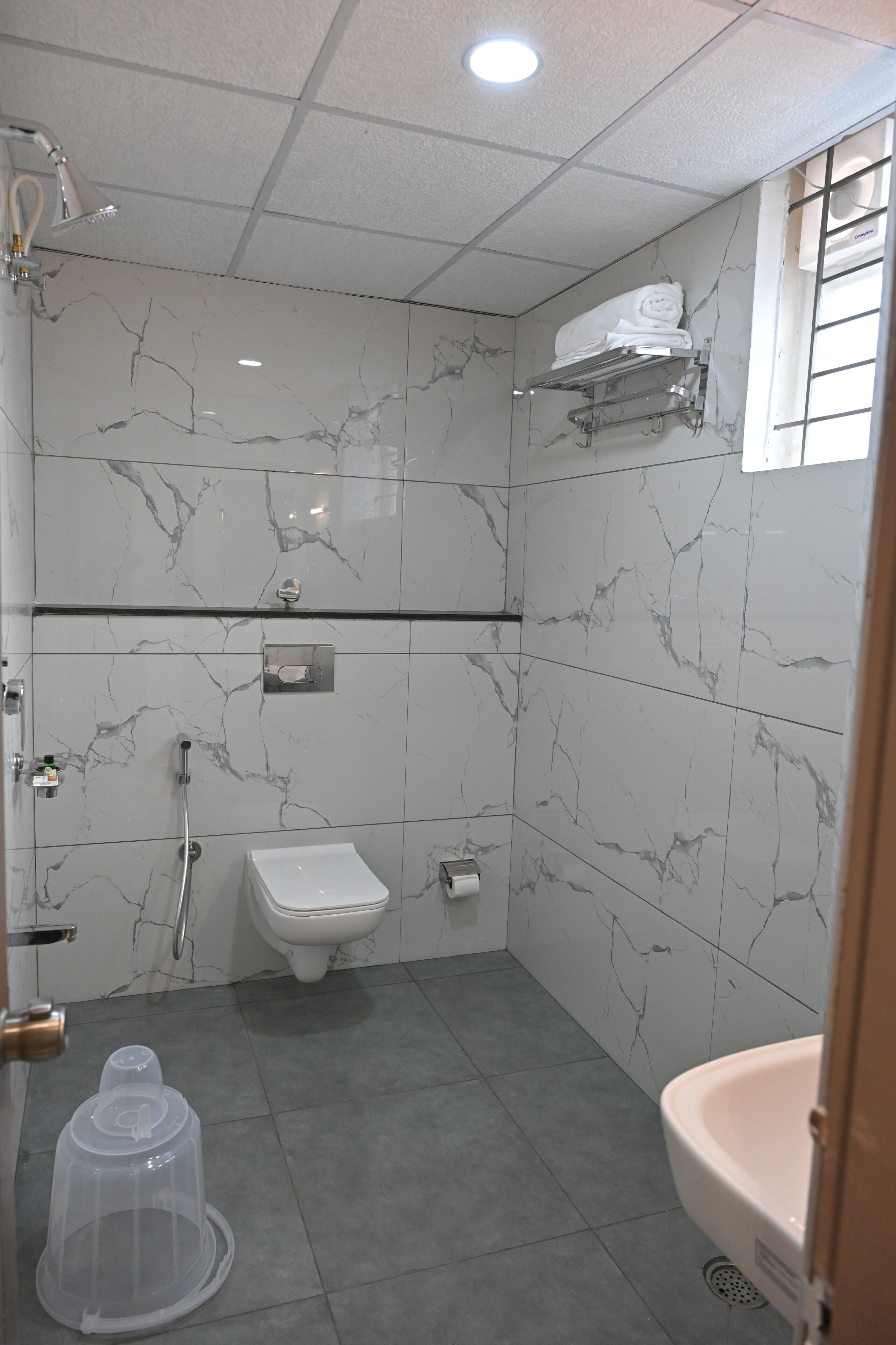 A bathroom with a toilet, sink, shower, and a towel rack.