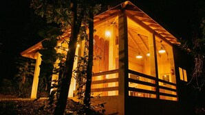 A wooden cabin with a sloped roof, large windows, and a porch area. - Indomitable Chalet @ El Yunque Zone (Benítez)