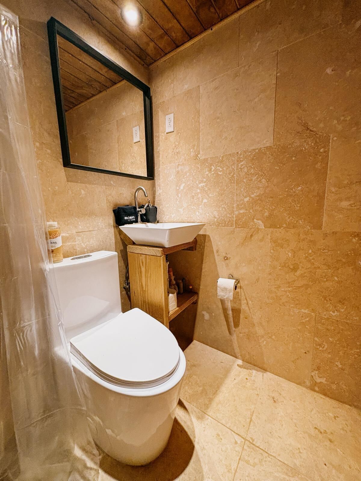 A bathroom with a toilet, sink, and mirror.