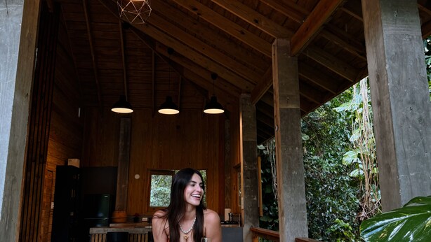 A wooden structure with a covered porch, a hanging light fixture, and a large leaf. - Indomitable Chalet @ El Yunque Zone (Benítez)