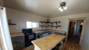 Una cocina con encimera de madera, estufa y estanterías con vajilla.