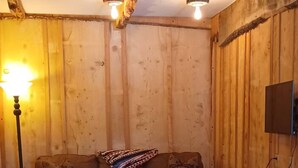 Una habitación acogedora con un muro de madera, un sofá marrón, dos sillas, una mesa de centro y una lámpara.