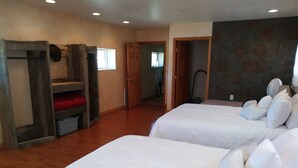Una habitación con dos camas, literas de madera, una silla roja y una pared de piedra.